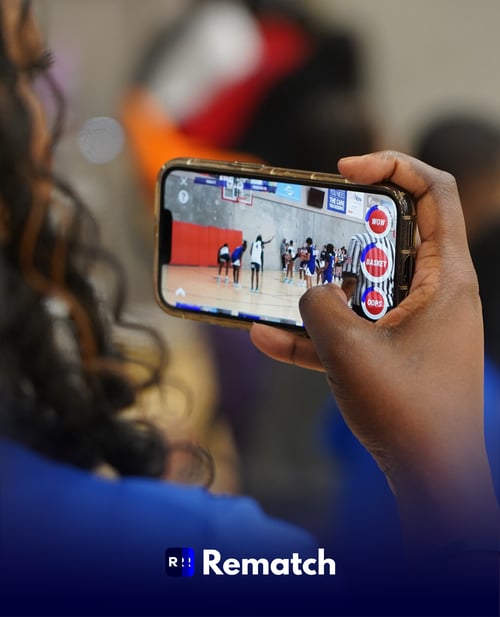 Woman holding a smartphone and capturing a basketball player shooting free throws on the Rematch app